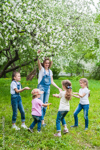 Woman and four little girls playing in blooming apple blossom garden. Family concept © Kiryakova Anna