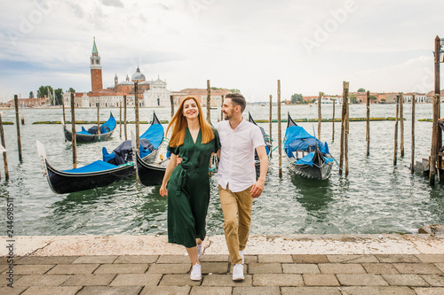 Young beautiful couple girl in a green dress a man in a white shirt walk near the water overlooking the Grand Canal in Venice Italy