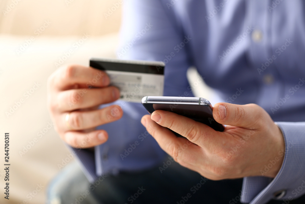 Male arms in suit hold credit card and phone make transfer Male arms in suit hold credit card and phone make transfer