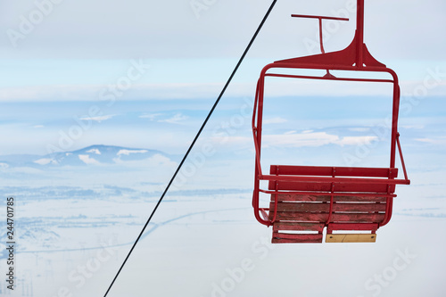 Empty old wooden chairlift against out of focus aerial urban area. Brasov, Romania.