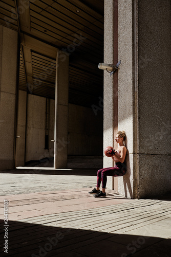 Fitness woman working out at outdoors gym using medicine ball. Sportswoman stretching outdoors with medicine ball. Copyspace for text