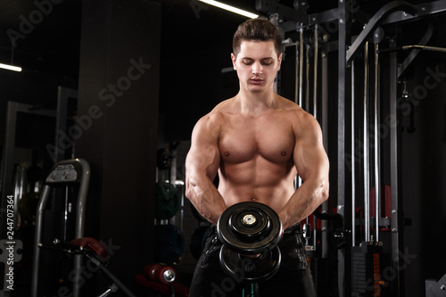 Athletic man working out with dumbbells in the gym.