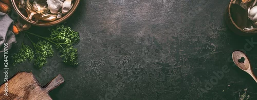 Obraz  z motywem Abstract food background. Top view of dark rustic kitchen table with wooden cutting board and cooking spoon, frame. Banner or template with copy space for your design. Kitchen utensils objects