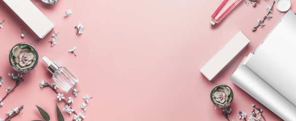 Pastel pink beauty desktop background with open magazine mock up, modern cosmetics and blossom branches, top view. Fashion blog and female business concept. Flat lay frame . Banner or template