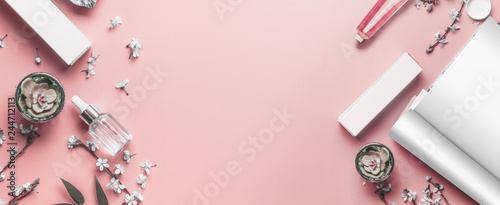 Pastel pink beauty desktop background with open magazine mock up, modern cosmetics and blossom branches, top view. Fashion blog and female business concept. Flat lay frame . Banner or template