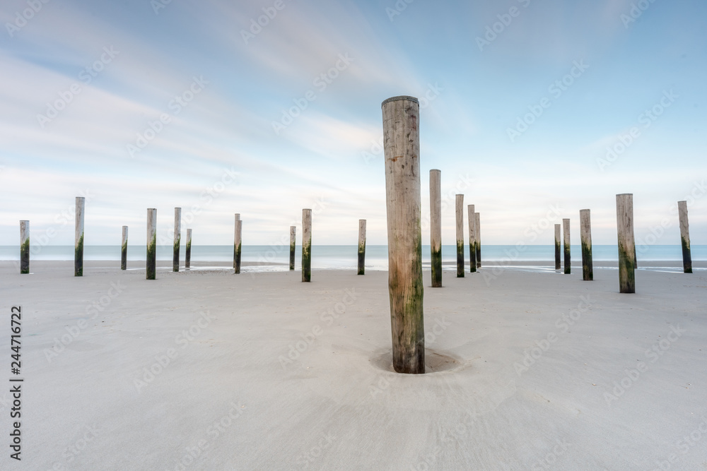 Poles on a beach with blue sky long exposure landscape Poles on a beach with blue sky long exposure landscape