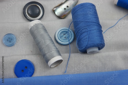 Combination of the colors at design of clothes, gray cotton fabric with bright blue one. Assortment of the accessories for sewing and needlework photo