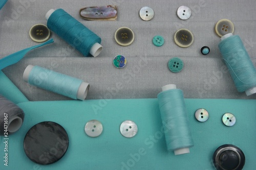 Combination of the colors at design of clothes, gray cotton fabric with turquoise one. Assortment of the accessories for the sewing and needlework