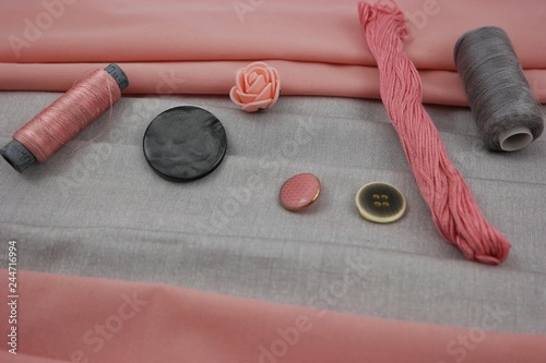 Combination of the colors at design of clothes, gray cotton fabric with pink one. Assortment of the accessories for sewing and needlework photo