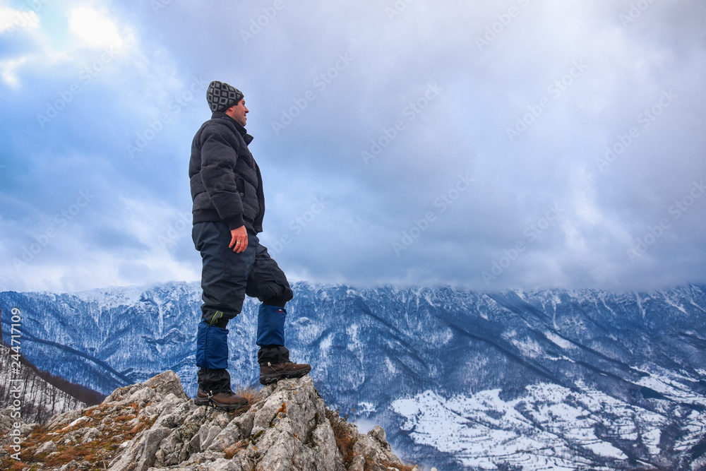 Hiker standing on a mountain top and looking into dynamic sky. Foggy mountain, Colorful winter landscape Hiker standing on a mountain top and looking into dynamic sky. Foggy mountain, Colorful winter landscape