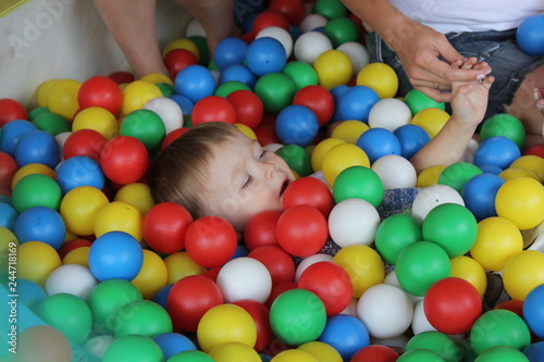 Mothers with babies plays in dry swimming pool and sits on the colored plastic balls.