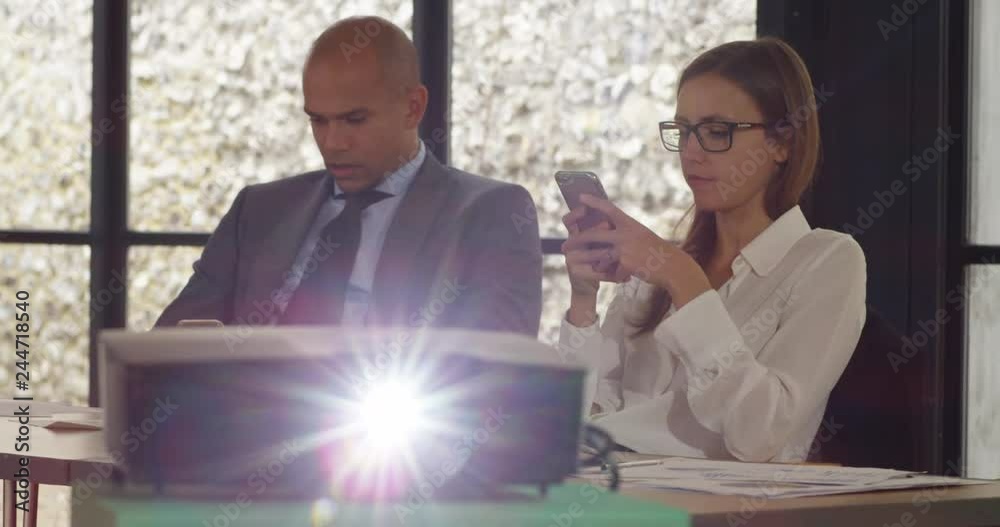 4K Business man & woman looking at smartphones during boring business presentation 4K Business man & woman looking at smartphones during boring business presentation