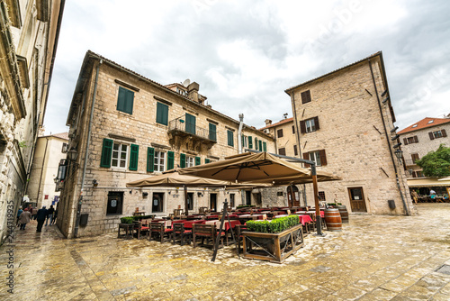 KOTOR, MONTENEGRO - MAY 11, 2017: The Main Square boasts many street cafes, tiny shops, scenic Kampana tower and the view on the foggy mountains on the background