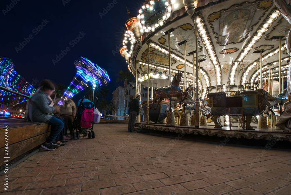 Fototapeta premium Abstract, long exposure shot of spinning Children's vintage Carousel at an amusement park in the evening and night illumination. Beautiful, bright carousel in Alicante, Spain 