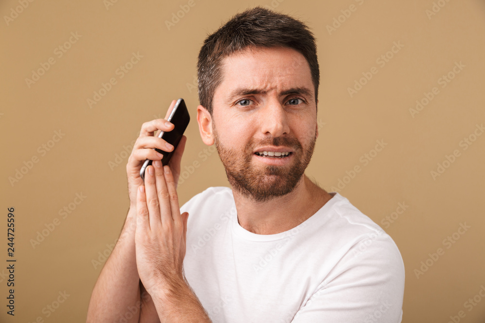Confused young casual man holding mobile phone Confused young casual man holding mobile phone