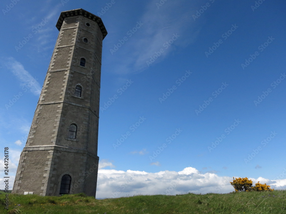 An old stone lighthouse against the blue sky on a sunny spring day in Wicklow, Ireland
