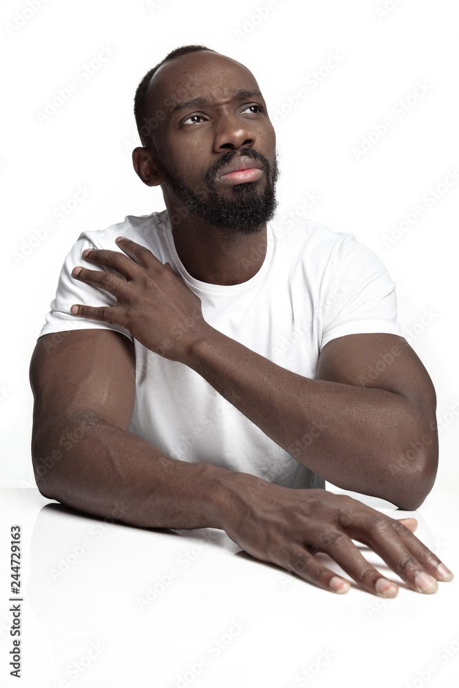 Portrait of a young serious african man at studio. High fashion male model posing and isolated on white background Portrait of a young serious african man at studio. High fashion male model posing and isolated on white background