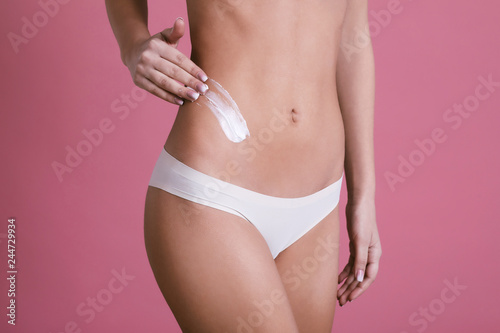 Body care. Woman applying cream on legs and buttocks 