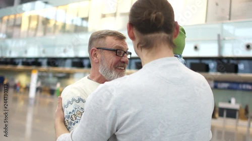 Grandpa first saw his little grandson. Mature man takes the hands of the baby. Grandfather, son and grandson. Meeting at the airport