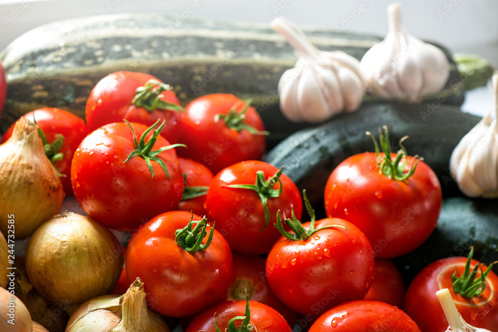 Ripe fresh harvested vegetables on table. Onions, tomatoes, garlic, pepper, zucchini in kitchen. Making delicious vegetarian meal or canning veggies for winter in jars. Concept of healthy eating