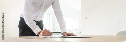 Photos Wide view image of businessman signing a document