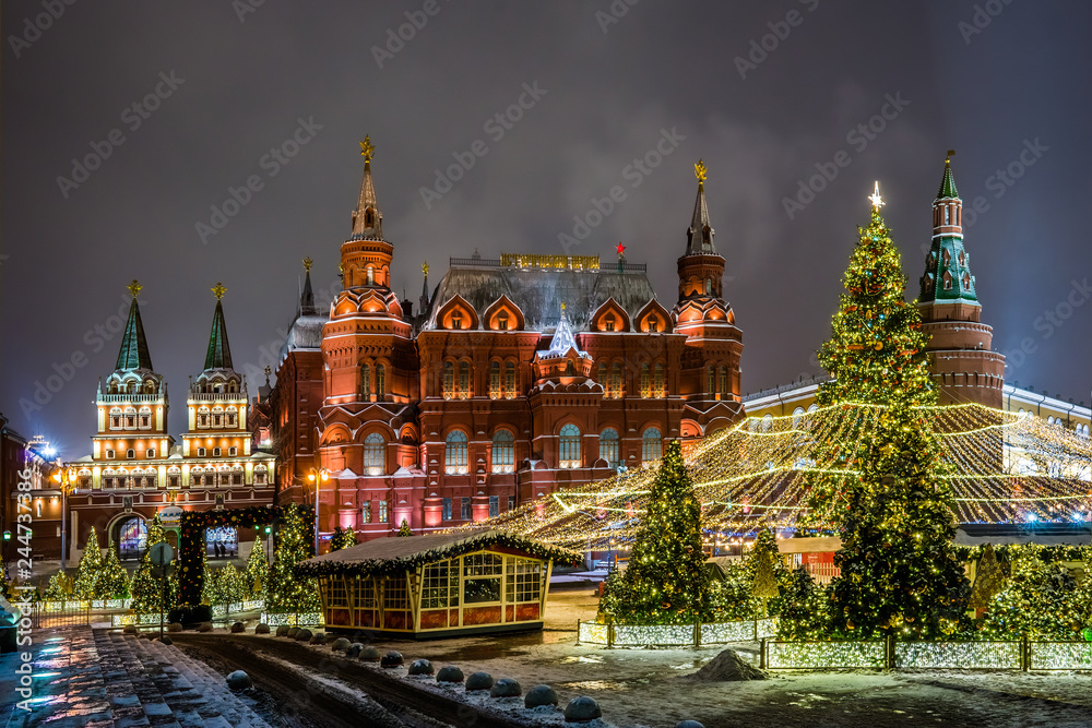 Winter night view of the big Christmas tree and decoration on the Manezhnaya square with the State historical Museum, Iverskaya chapel and Uglovaya Arsenal'naya tower of Kremlin in Moscow, Russia.