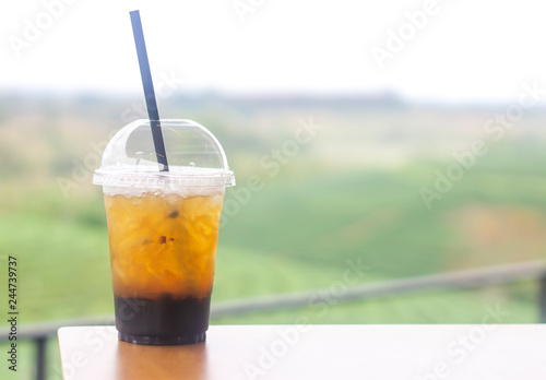 Cup plastic of ice tea on wooden table in the garden