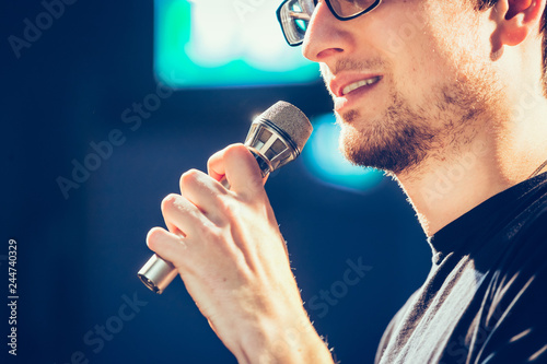 Speaker on the stage: Young Caucasian man is talking into a mirophone photo