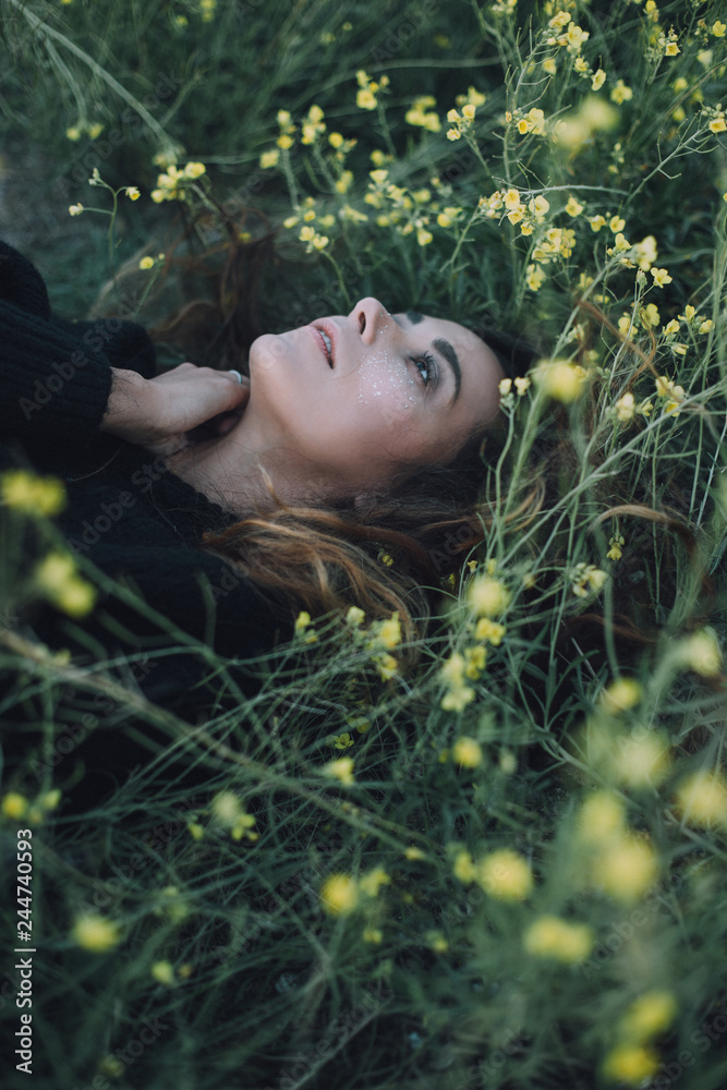 Young beautiful woman with a bright shining make up on a green meadow with yellow flowers Young beautiful woman with a bright shining make up on a green meadow with yellow flowers
