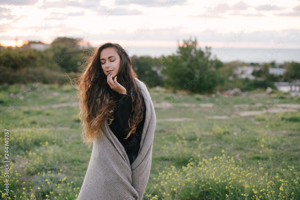 Young beautiful woman with a bright shining make up on a green meadow with yellow flowers