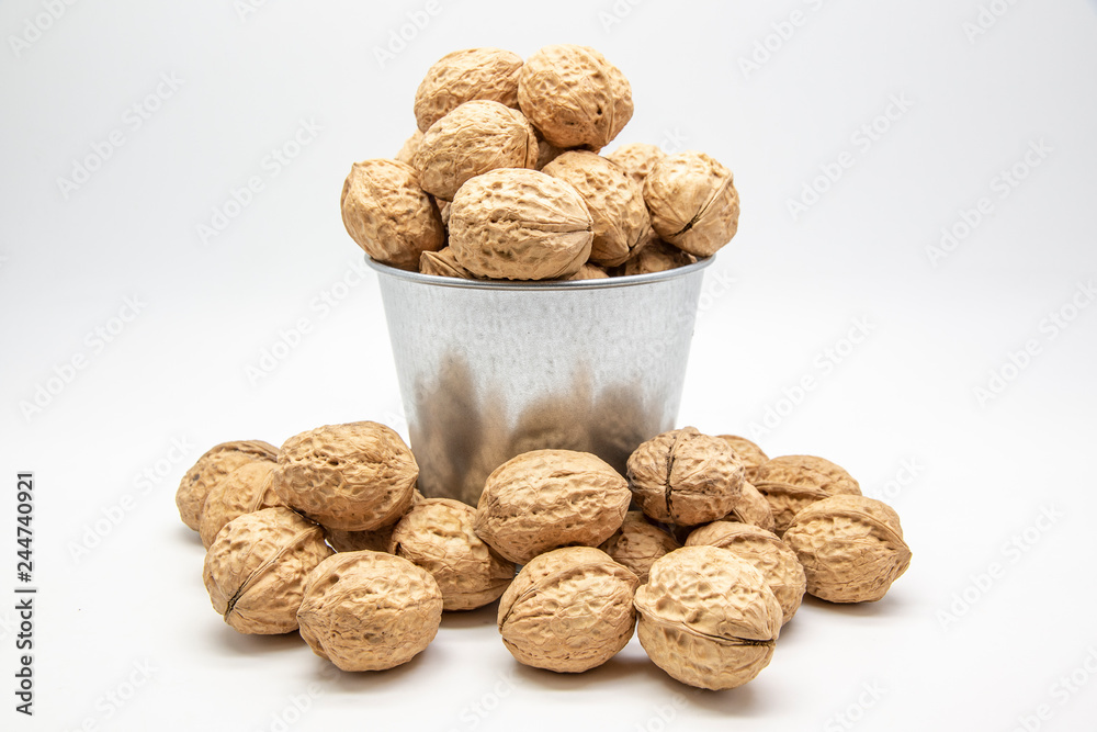 Walnuts in a tin bucket on white background. Walnuts in a tin bucket on white background.