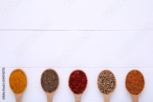 Spices mix on wooden spoons on a white wooden background. Top view