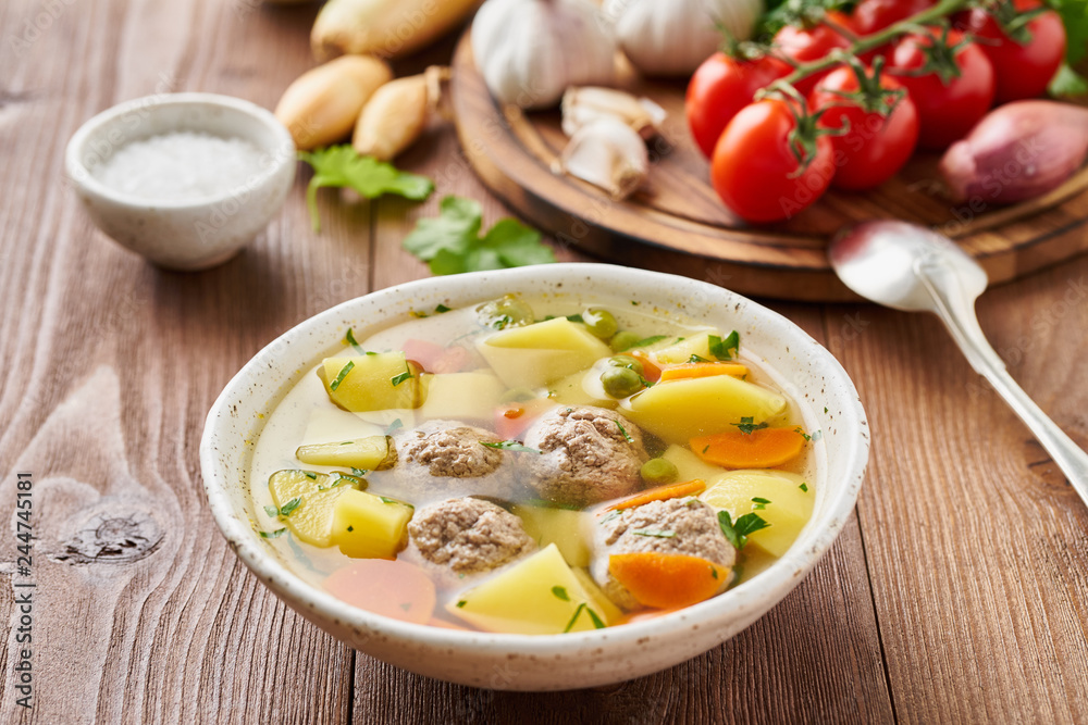 meatballs soup in white plate on old wooden rustic brown table, side view meatballs soup in white plate on old wooden rustic brown table, side view