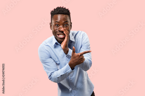 Secret, gossip concept. Young afro man whispering a secret behind his hand. Businessman isolated on trendy pink studio background. Young emotional man. Human emotions, facial expression concept. photo