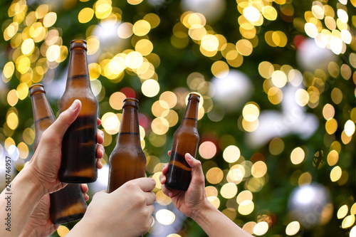 Photography Hands holding beer bottles and happy enjoying harvest time together to clinking glasses at outdoor party on beautiful bokeh night light background