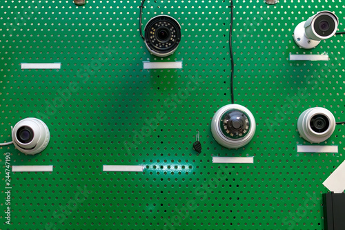 samples of CCTV cameras hung on a green metal stand in the store for demonstration