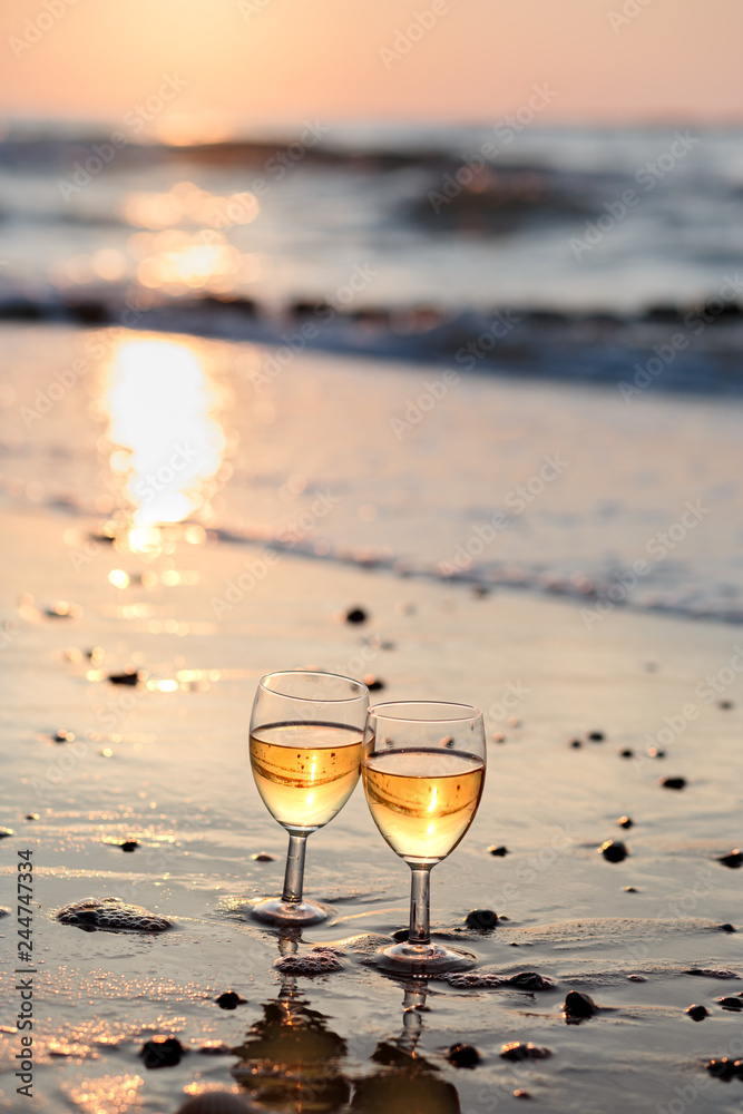 Two wine glasses with white wine standing on beach