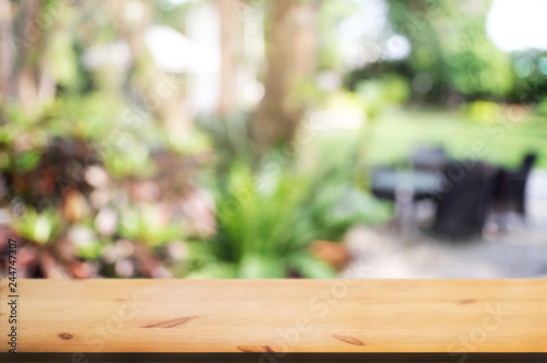 wooden table in front of blurred home / cafe in garden background