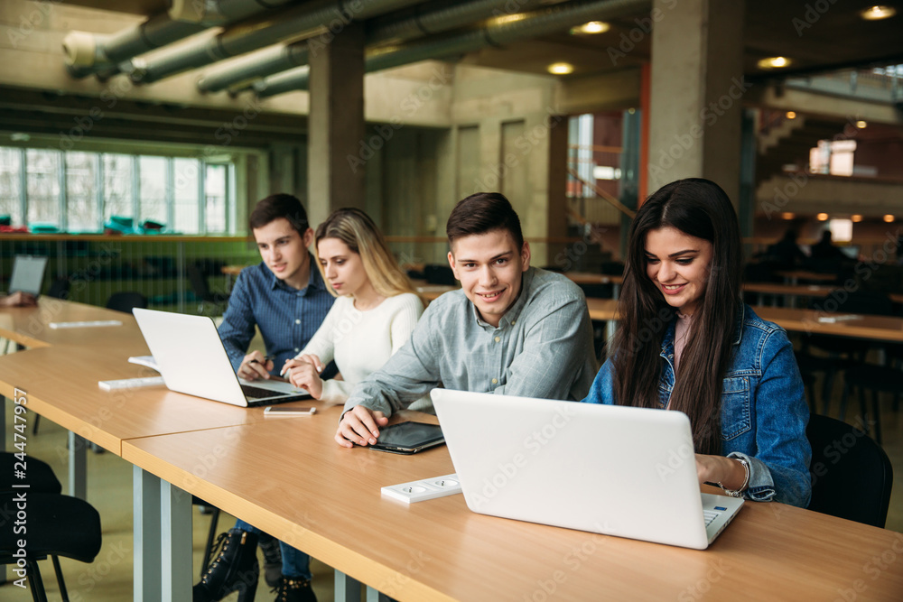 Group of college students studying in the school library, a girl and a boy are using a laptop and connecting to internet. Prepare for an exam Group of college students studying in the school library, a girl and a boy are using a laptop and connecting to internet. Prepare for an exam