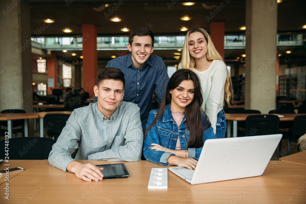 Group of college students studying in the school library, a girl and a boy are using a laptop and connecting to internet. Prepare for an exam Group of college students studying in the school library, a girl and a boy are using a laptop and connecting to internet. Prepare for an exam