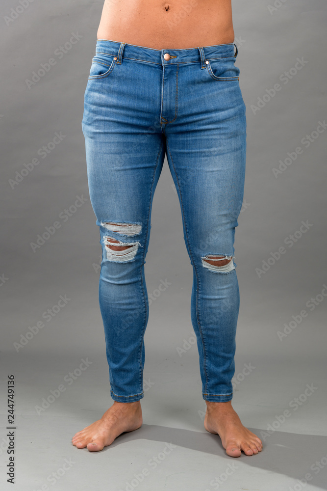Modern male unbranded Blue skinny ripped jeans isloated on grey background Modern male unbranded Blue skinny ripped jeans isloated on grey background