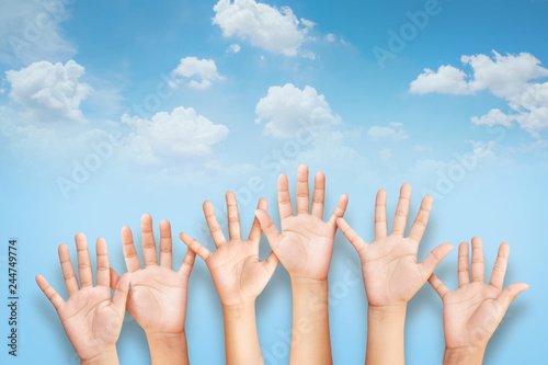 kids Raising hands up together with blue sky and clouds background