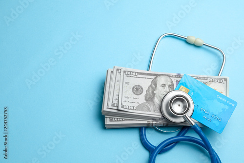 Stack of cash dollars and credit card with stethoscope on blue background. The concept of medical strechevka or expensive medicine, doctors salary.