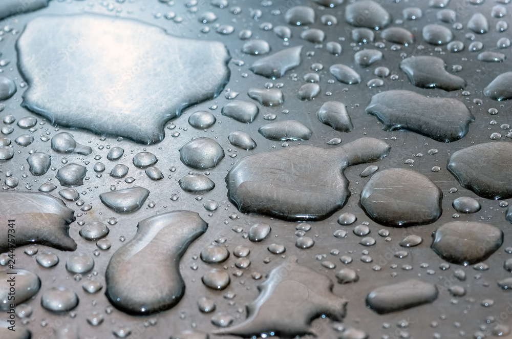 water droplets lie on a silvery metal surface water droplets lie on a silvery metal surface