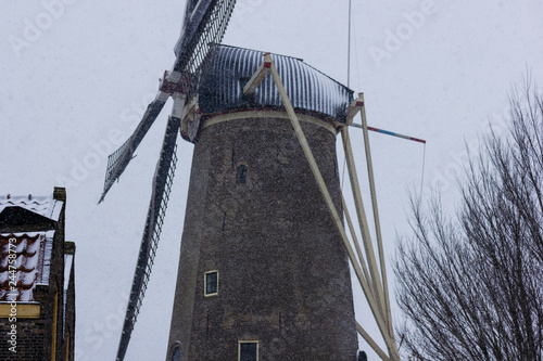 Gouda, South-Holland/The Netherlands - January 22 2019: First real snow in the Netherlands in 2019 a walk through the inner city of Gouda Roode Leeuw windmill photo