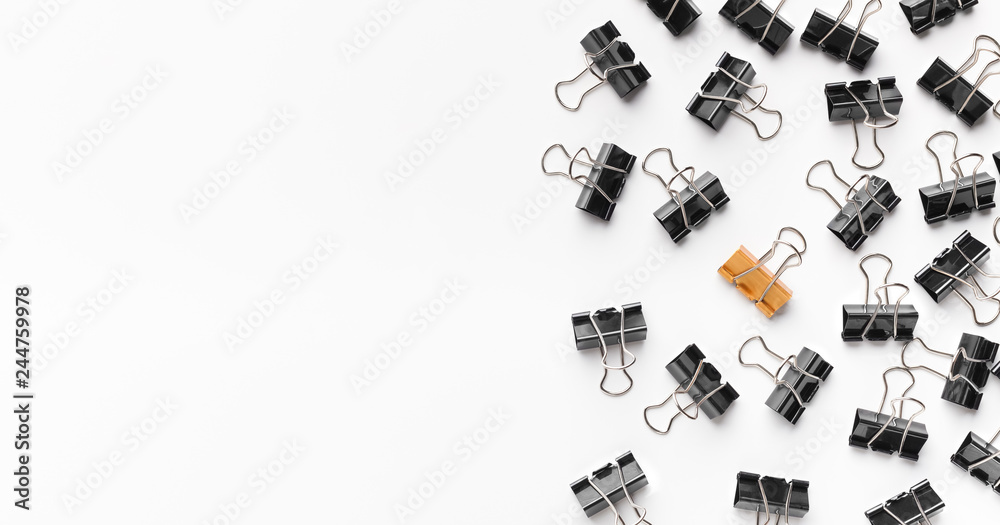 Golden binder clip standing between black ones Golden binder clip standing between black ones