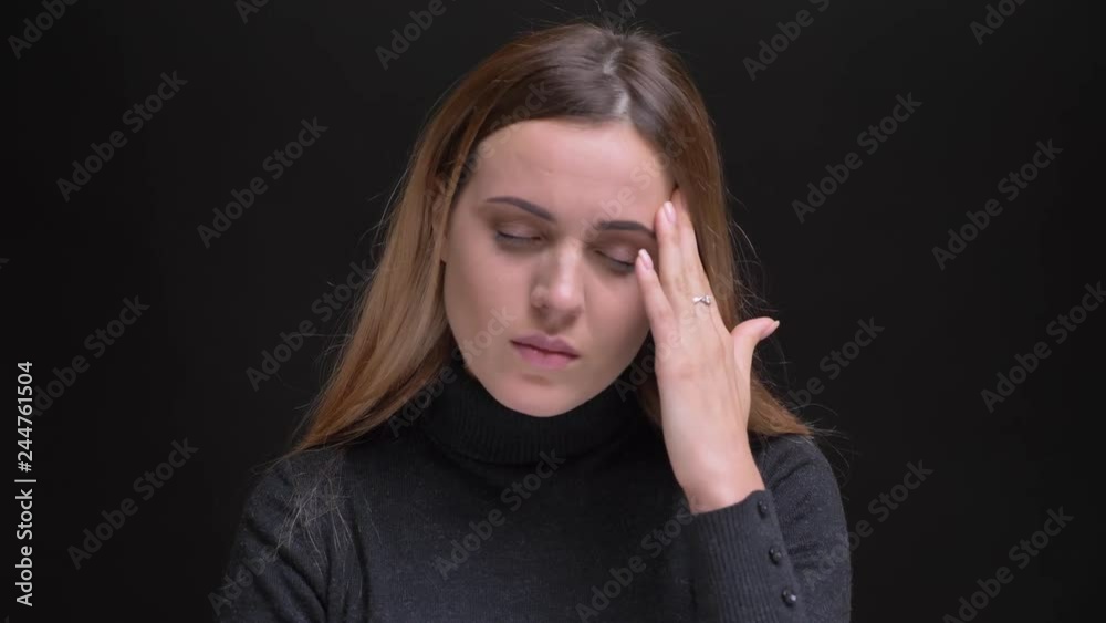 Portrait of young caucasian long-haired blonde girl having headache and making massage on black background. Portrait of young caucasian long-haired blonde girl having headache and making massage on black background.