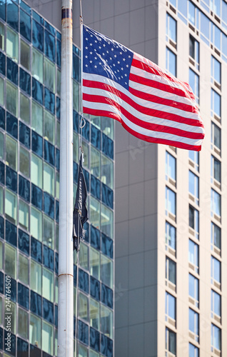 Flying American Flag with modern buildings in background, selective focus, New York, USA.