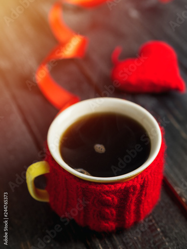 coffee mug and heart on wooden background.