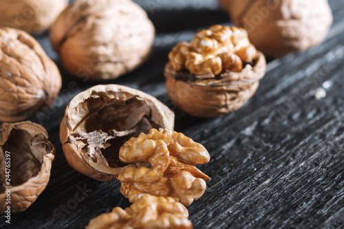 Whole walnuts and their kernels on a wooden dark table close-up with copyspace